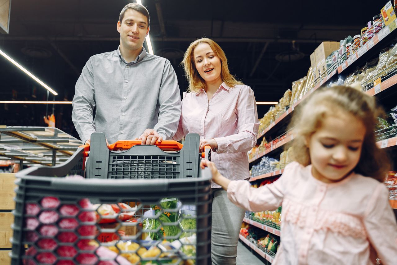 Happy family enjoying a fun shopping trip together in a supermarket aisle.